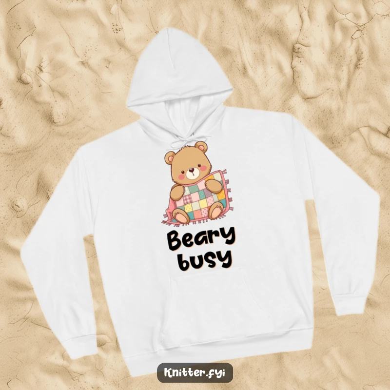 Funny Bear Hoodie: A determined bear proudly sews a cozy patchwork quilt, perfect for staying warm.
