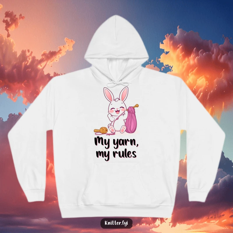 Funny hoodie with a cute, joyful bunny character in the act of threading a giant sewing needle with colorful yarn, a cozy crafter's delight.